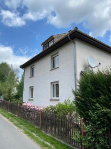 ein weißes Haus mit einem Zaun davor in der Unterkunft FEWO am Wald in Krauschwitz