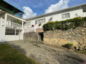 a white house with a stone wall next to a building at CASA CAMPESTRE VILLA JULIA in Quetame