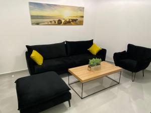 a living room with a black couch and two chairs at Sima Suite 2 in Ashdod