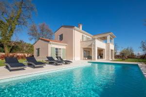 a villa with a swimming pool in front of a house at Villa Iris by ILC (Istria Luxury Collection) in Brtonigla