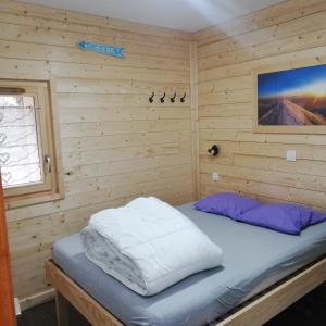 ein Schlafzimmer mit einem Bett in einer Holzwand in der Unterkunft Chalet Les Garands in Valmeinier