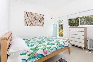 1 dormitorio con 1 cama con colcha de flores en Sojourne en Shoalhaven Heads