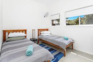 two beds in a room with two windows at Sojourne - Walk to beach and Golf Club! in Shoalhaven Heads