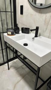 a white bathroom sink with two pots on it at Apartman Lux in Žepče