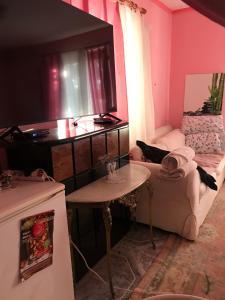 sala de estar con paredes de color rosa y mesa en Külön apartman fiatal pároknak hosszútávra feléért!, en Budaörs