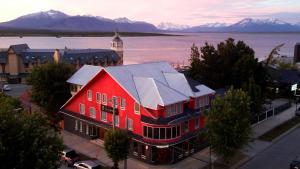 un grand bâtiment rouge avec une tour d'horloge dans une ville dans l'établissement Darwin Hotel, à Puerto Natales