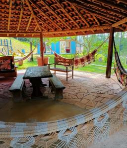 d'une terrasse avec un hamac, une table et des bancs. dans l'établissement Aconchego no Campo, à São Roque