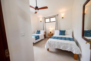 1 Schlafzimmer mit 2 Betten und einem Deckenventilator in der Unterkunft Oasys House - Beautiful Private Beach Front Home in Msambweni