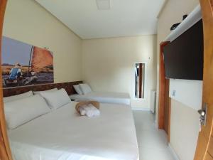 a bedroom with a white bed with a stuffed animal on it at POUSADA DOS LAGOS in Paulino Neves