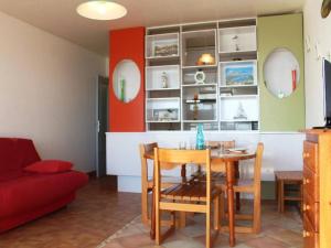uma sala de jantar com uma mesa e um sofá vermelho em Appartement Port-la-Nouvelle, 2 pièces, 4 personnes - FR-1-229C-170 em Port-la-Nouvelle