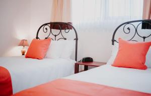 2 camas con almohadas de color naranja y blanco en una habitación en Frenold Inn, en Potrerillos