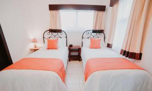 2 Betten in einem Zimmer mit orangefarbenen Kissen in der Unterkunft Frenold Inn in Potrerillos