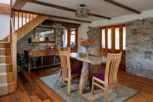 a dining room with a wooden table and chairs at The Old Coach House - Converted barn with private garden parking and fireplace in Totnes