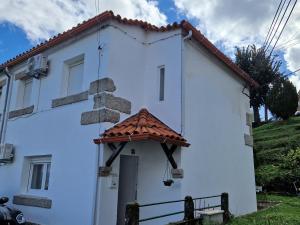 une maison blanche avec un toit rouge dans l'établissement Moradia T2 em bairro pitoresco da Covilhã, à Covilhã