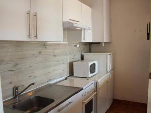 uma cozinha com armários brancos, um lavatório e um micro-ondas em Appartement Port-la-Nouvelle, 2 pièces, 4 personnes - FR-1-229C-20 em Port-la-Nouvelle