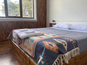 Un dormitorio con una cama con una manta. en Hostal Ochen, en Punta Arenas