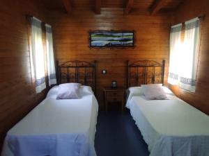 - 2 lits dans une chambre dotée de murs en bois et de fenêtres dans l'établissement Rosa de la contrera, à Tarifa