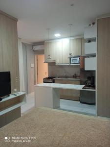 cocina grande con armarios blancos y TV en Flat Residencial Simas, en Florianópolis