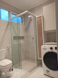 een badkamer met een douche, een toilet en een wasmachine bij Flat Residencial Simas in Florianópolis
