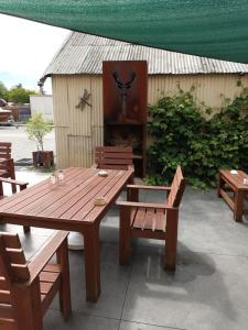 a wooden picnic table and benches with a fireplace at Ahaura Hotel in Greymouth
