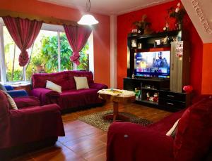 a living room with purple furniture and a tv at Casa de Alondras in Panajachel