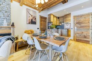 a dining room with a wooden table and white chairs at Appartement style chalet 5* vue Mont-Blanc - Arc 1950 in Arc 1950