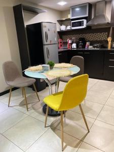 eine Küche mit einem Tisch mit Stühlen und einem gelben Stuhl in der Unterkunft Bellini luxury - Puerto Santa Ana in Guayaquil