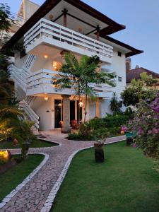 a white house with a walkway in front of a yard at Hotel Grand Kumala Bali in Legian