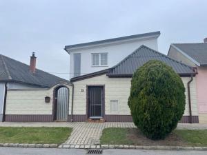 a white house with a tree in front of it at Cheap Outlet Center Apartment with Pool in Parndorf