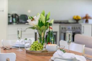 una mesa de comedor con una botella de champán y uvas en Banyula Annex en Burradoo