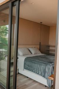 a bedroom with a bed and a glass wall at Casas na montanha - Villa Montegrappa in Caxias do Sul