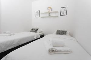 two beds in a white room with towels on them at Apartman Mirna Vinkovci in Vinkovci