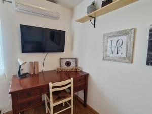 a room with a wooden desk with a television on a wall at Moradia T2 em bairro pitoresco da Covilhã in Covilhã