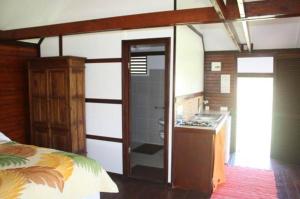 1 dormitorio con 1 cama y baño con lavamanos en Raiatea Airport Bungalow, en Uturoa