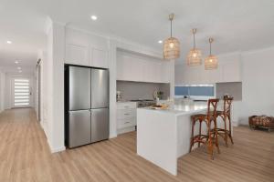 a kitchen with white cabinets and a refrigerator at The Quarterdeck in Callala Bay
