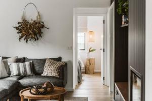 a living room with a gray couch and a table at The Lull Culburra in Culburra Beach