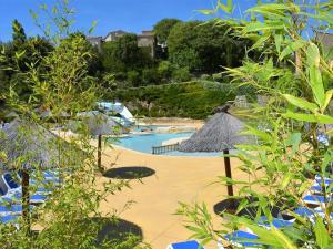 a swimming pool with straw umbrellas on a beach at Maison Duplex 3P 6 Pers avec Piscines, Terrasses, Parking et Animaux Admis - Salavas - FR-1-382-16 in Salavas +6 photos