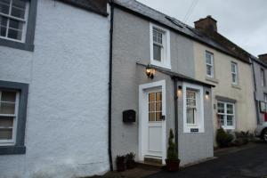a white house with a white door on a street at The Burrow in Kelso