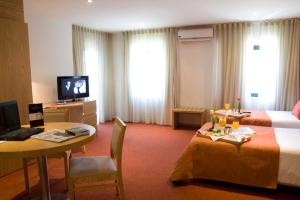 a hotel room with a bed and a desk and a table at Paredes Hotel Apartamento in Paredes