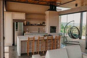 a kitchen with a island with a bar with chairs at Casas na montanha - Villa Montegrappa in Caxias do Sul