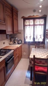 a kitchen with wooden cabinets and a table and a stove at La Casa Rossa - Presolana in Castione della Presolana