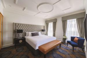 Habitación de hotel con cama y silla en The Savoy Hotel on Little Collins Melbourne, en Melbourne