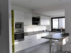 a kitchen with white cabinets and a table in it at Maison Ruoms, 4 pièces, 6 personnes - FR-1-382-96 in Ruoms