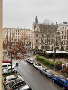 eine Stadtstraße mit Autos, die vor einem Gebäude geparkt sind in der Unterkunft Cozy Studio-Apartment - Südplatz in Leipzig