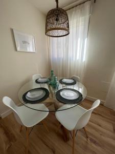 a dining room with a glass table and white chairs at Apartamento Córboba Centro in Córdoba