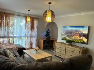 Beautiful and comfy 3 bedrooms duplex close to everything في Budgewoi: غرفة معيشة مع أريكة وشجرة عيد الميلاد