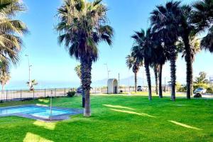 een park met palmbomen en een zwembad bij La Serena - Departamento Frente al Mar in La Serena +3 foto's