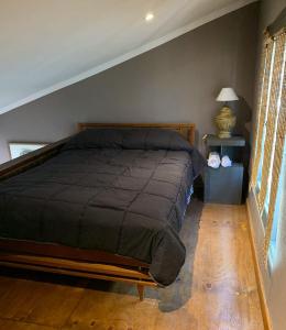 een slaapkamer met een bed met een zwart dekbed bij Hidden Twins Cabañas de montaña Cacheuta in Cacheuta