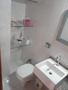 a white bathroom with a toilet and a sink at Casa de Lençóis in Lençóis