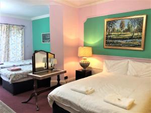 a bedroom with a bed and a desk with a mirror at Lyttleton Lodge in Uxbridge